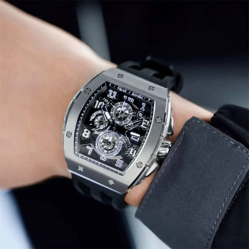 The TSAR BOMBA Elemental TB8211Q Stainless Steel Tonneau Chronograph Watch. Features a stainless steel case and a Seiko quartz movement. The multi-layered skeleton dial combines date display and chronograph functions. A 1/20th-second chronograph subdial is located at 12 o'clock, the date display at 3 o'clock, the hour/minute chronograph subdial at 6 o'clock, and the chronograph seconds subdial at 9 o'clock.-- Model wearing display