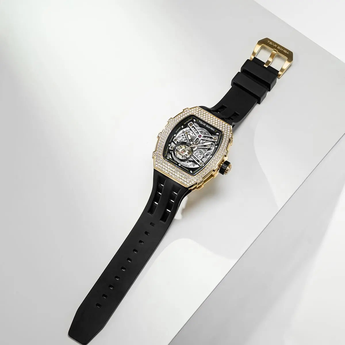 A TSAR BOMBA tonneau skeleton watch with a black strap and a cubic zirconia diamond bezel. It lies flat on a table.