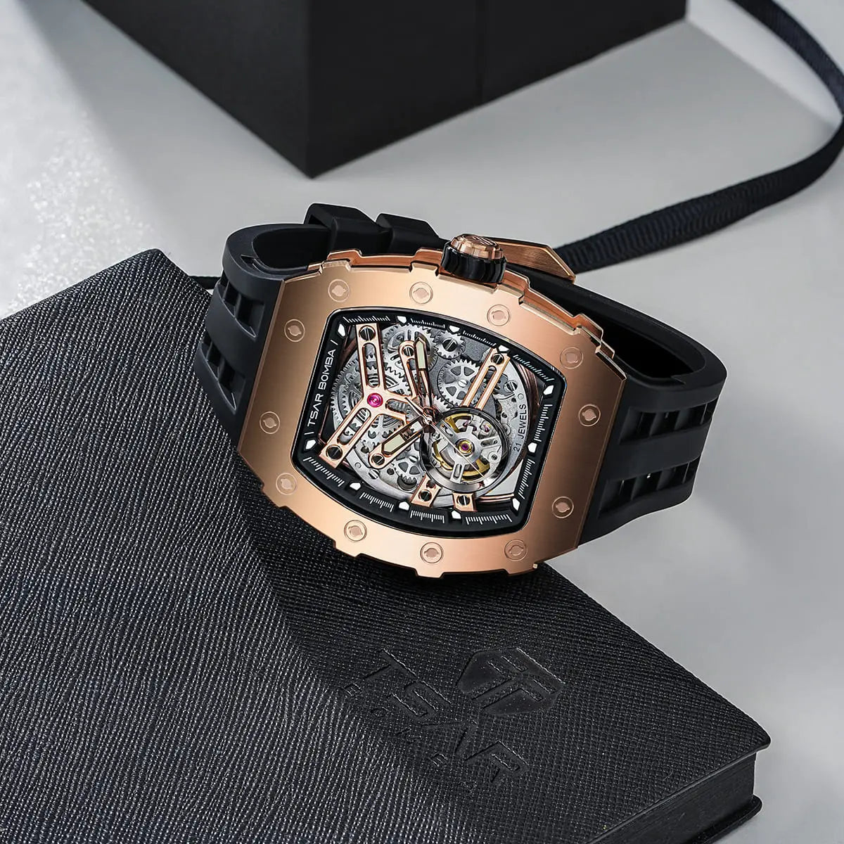 TSAR BOMBA TB8208A rose gold-tone tonneau skeleton watch with a black strap, displayed on a textured black presentation box.