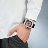 TSAR BOMBA TB8208A rose gold-tone tonneau skeleton watch with a black strap, worn with a white sweater.
