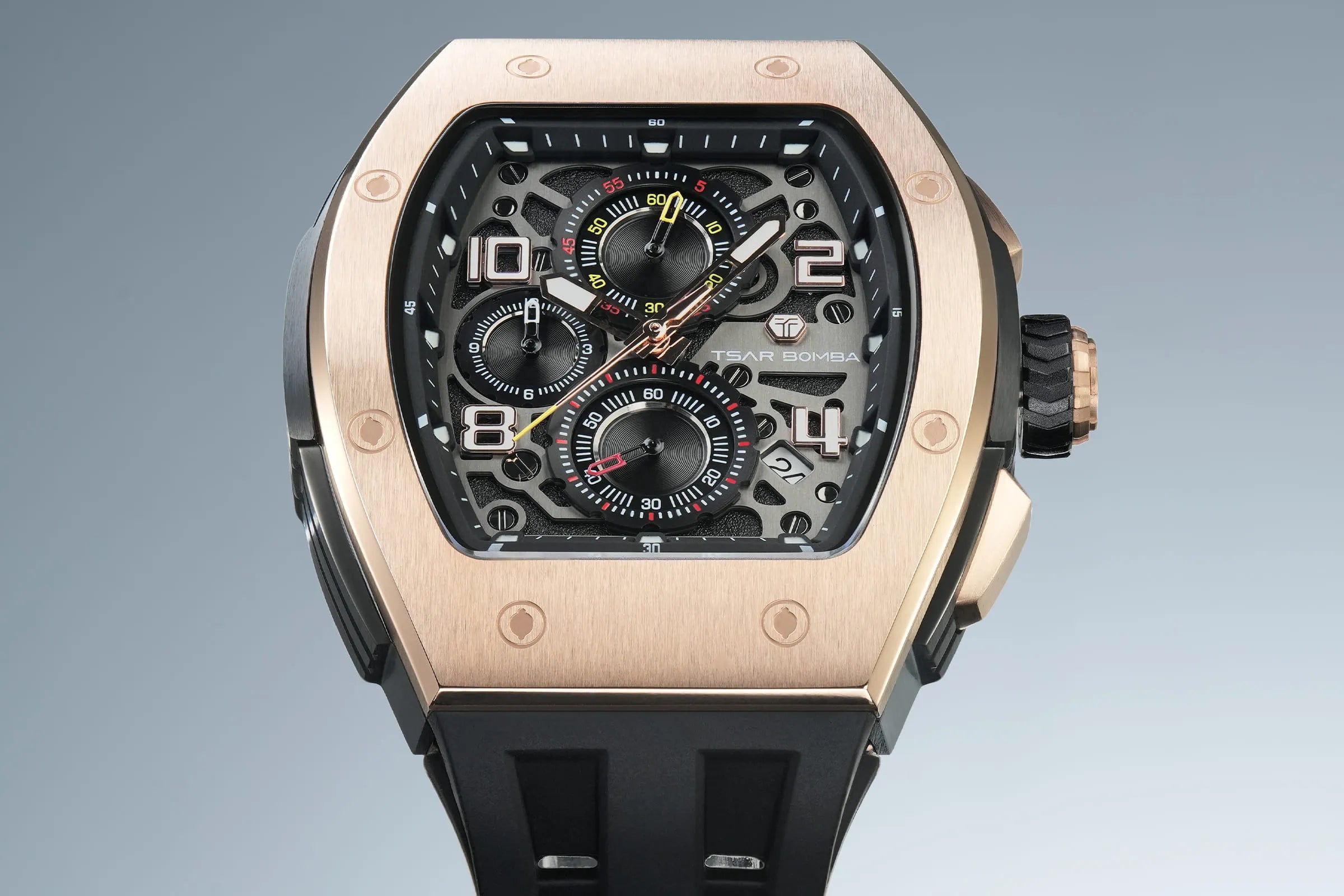 The TSAR BOMBA Elemental TB8224Q stainless steel tonneau quartz watch.Golden bezel and black strap.  The Multifunction dial design, the multifunction dial features a chronograph minute sub-dial at the 12 o'clock position, a date display between the 4 and 5 o'clock positions, a seconds sub-dial at the 6 o'clock position, and an hour chronograph sub-dial at the 9 o'clock position. --Top-down-view Blue-and-white gradient background