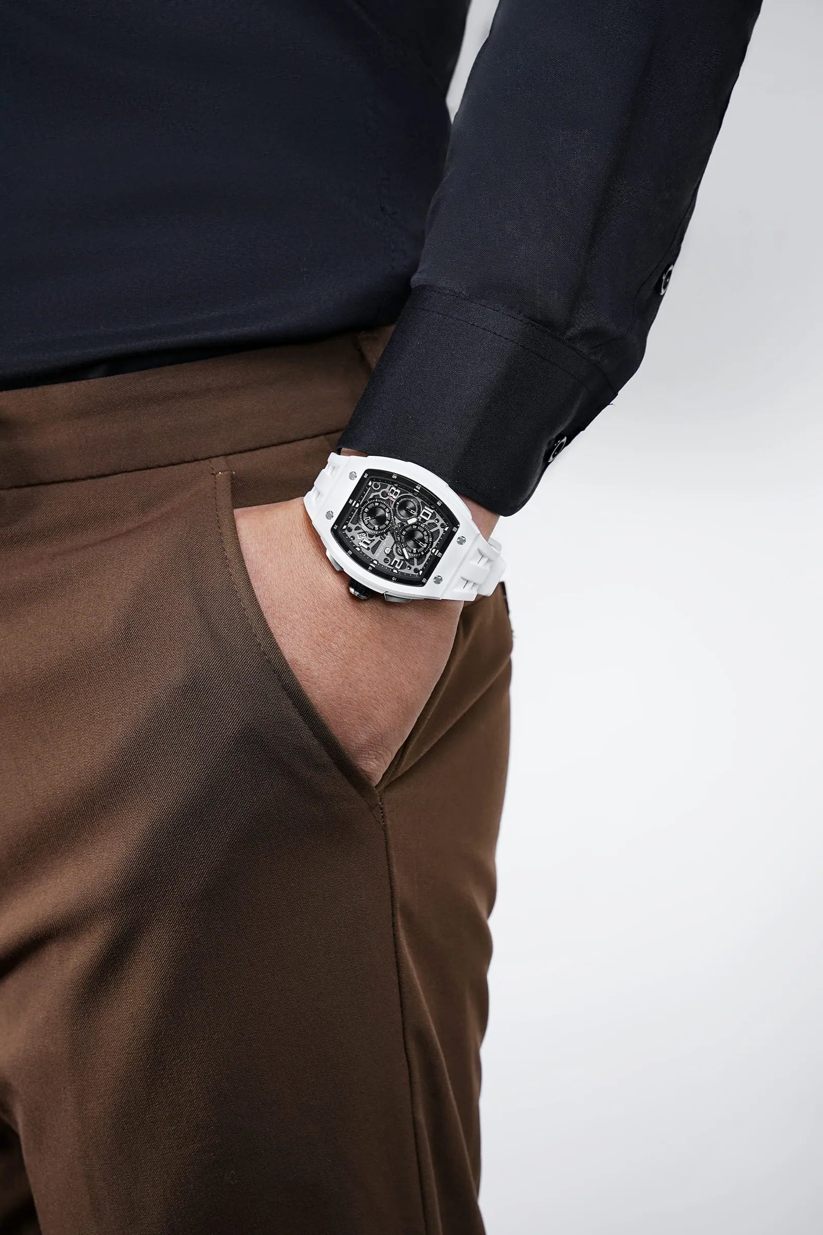 In the photo, a male model seated in a chair wears the TB8224B watch on his wrist, with the dial facing the viewer; the watch features an white strap and white ceramic case. This highlights the stylish look of this barrel-shaped watch when worn.
